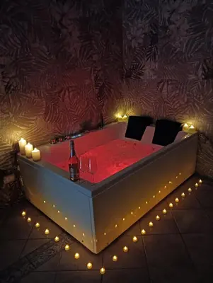 a tub with a table and chairs in a room with lights at Dojo idro rooms in Carini