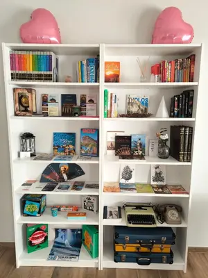 a white book shelf filled with lots of books at Selenite Home in Palermo