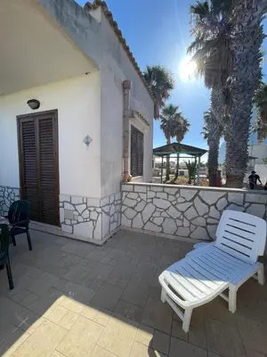 a patio with a white chair and a wall at Appartamento Gelsomino in San Vito lo Capo