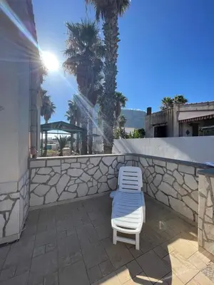 a chair sitting on a patio next to a wall at Appartamento Gelsomino in San Vito lo Capo
