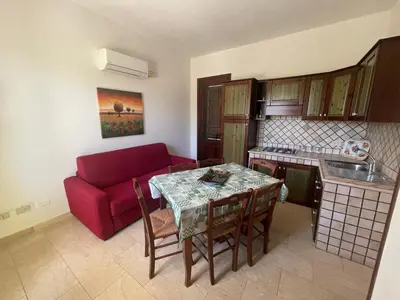 a living room with a table and a red couch at Appartamento Giglio in San Vito lo Capo