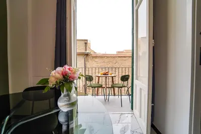 a glass table with a vase of flowers on a balcony at Quattro Canti 200 mt- Appartamento Salvia in Palermo