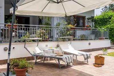 a patio with two chairs and an umbrella at More Holidays Beach in Mondello