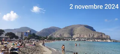 a group of people on a beach with mountains in the background at palermo cloister dream house in Palermo