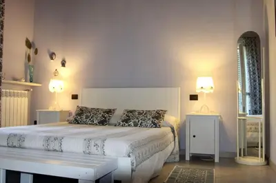 a bedroom with a white bed with two tables and a mirror at Villa Enza Bellissima villa con piscina in Terrasini