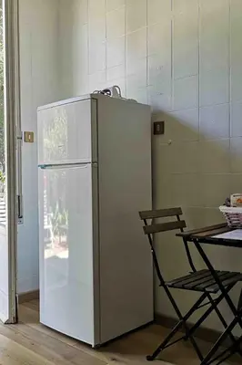 a white refrigerator next to a table and a chair at Villa Marea Mondello in Palermo