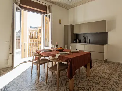 a dining room with a table and a kitchen at Casa Disìu in Palermo