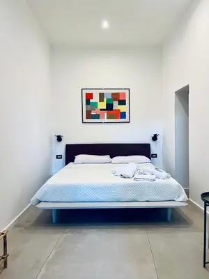 a bed in a bedroom with a painting on the wall at Guest House Colonna apt in Palermo