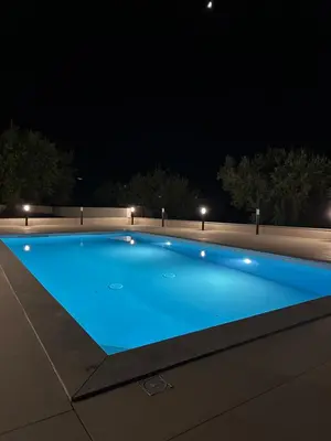 a large blue swimming pool at night at Villa Valentina in Altavilla Milicia