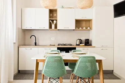 a kitchen with white cabinets and green chairs at Verdeacqua Home in Castellammare del Golfo
