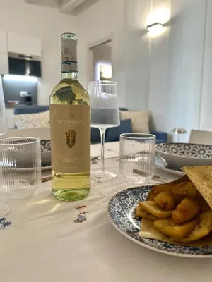a bottle of wine sitting on a table with a plate of food at Nika Palermo Holiday House in Palermo
