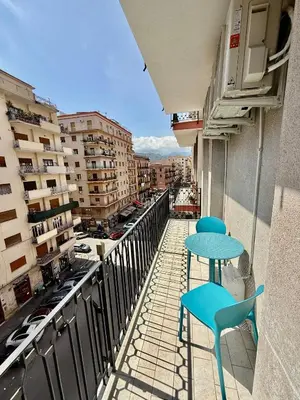 a table and chairs on a balcony with a view of a city at La Zisa Luxury Apartment in Palermo