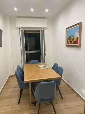 a dining room with a wooden table and blue chairs at La Zisa Luxury Apartment in Palermo