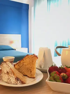 a plate with a piece of cake and a bowl of strawberries at Hotel Conchiglia d'Oro in Mondello
