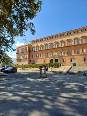 two people standing in a parking lot in front of a building at Difronte Palatina Chapel in Palermo