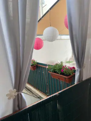 a balcony with potted plants and white curtains at Casa dei nonni di Yuri in Palermo