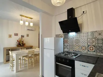 a kitchen with a refrigerator and a table with chairs at Casa3Fratelli, via Cutino 16 in Isola delle Femmine