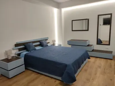 a bedroom with a blue bed and a mirror at DH Studio Apartments in Castellammare del Golfo