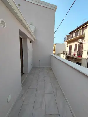 an empty balcony of a white building with a tile floor at DH Studio Apartments in Castellammare del Golfo