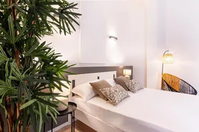 a white bed in a room with plants at Diletti Rooms in Palermo