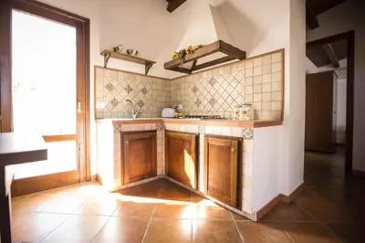 a kitchen with wooden cabinets and a large window at Appartamento Le Terrazze in Castellammare del Golfo