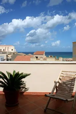 a chair on a balcony with a view of the ocean at Appartamento Le Terrazze in Castellammare del Golfo
