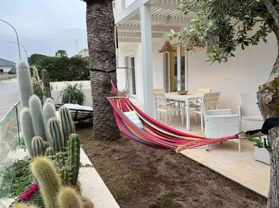 a hammock in the yard of a house with cactus at Villa Ippolita - 2 Bedrooms Apartment with Exclusive Garden in San Vito lo Capo
