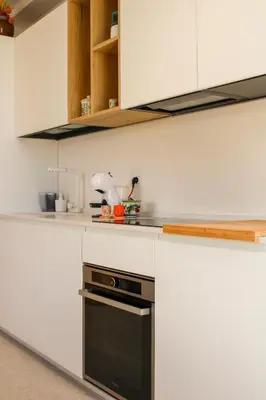 a kitchen with white cabinets and a black oven at Villa Ippolita - 2 Bedrooms Apartment with Terrace & Garden Exclusive in San Vito lo Capo