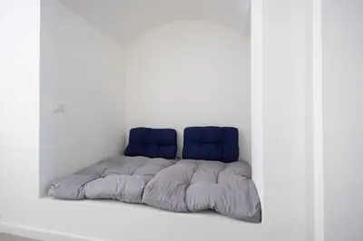 a bed with two blue pillows in a white room at iFlat Porta di Mare 45 in Palermo