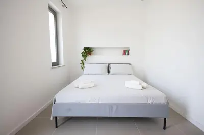 a white bed in a white room with a window at iFlat Porta di Mare 45 in Palermo