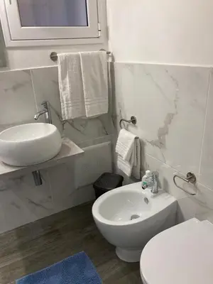 a white bathroom with a sink and a toilet at Casalabruto in Bagheria