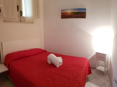 a bedroom with a red bed with a white pillow on it at Casa Limone in San Vito lo Capo