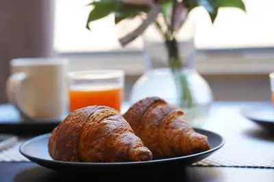 two croissants and bread on a plate on a table at 200 mt Quattro Canti- Appartamento Rovere in Palermo