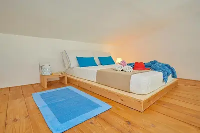 a bedroom with a bed with blue pillows and a blue rug at Villa Ginestra - Scopello-Villas in Scopello