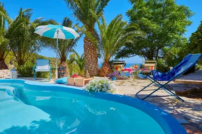 a swimming pool with a chair and an umbrella at Villa Ginestra - Scopello-Villas in Scopello