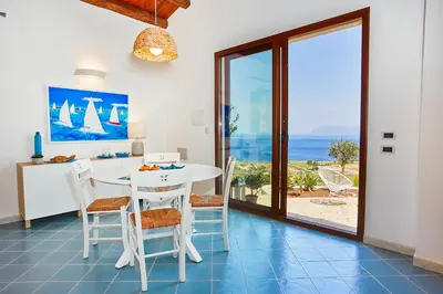 a dining room with a table and a view of the ocean at Villa Brezza Marina - Scopello-Villas in Scopello
