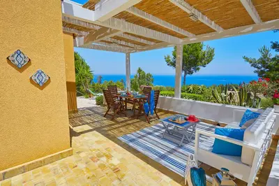 a patio with a table and chairs and the ocean at Villa Desirée - Scopello-Villas in Scopello