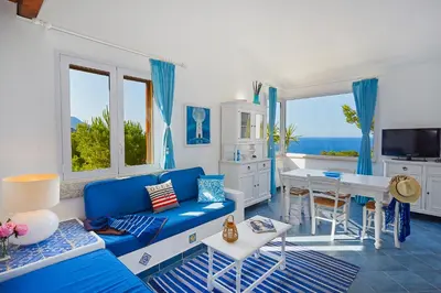 a living room with a blue couch and a table at Villa Desirée - Scopello-Villas in Scopello