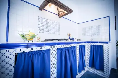 a kitchen with blue curtains and a sink at Appartamento La Marina in Castellammare del Golfo