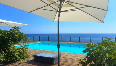 an umbrella and a pool with the ocean in the background at Il Casale San Vito in San Vito lo Capo