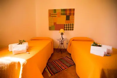 two beds in a room with orange sheets at Villa Chiara in Scopello
