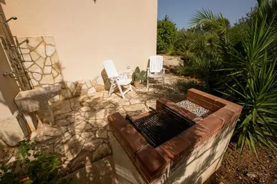 a patio with two white chairs and a couch at Villa Chiara in Scopello