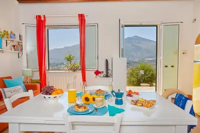 a white table with food on it in a room with windows at Villa Rosa Dei Venti - Scopello-Villas in Scopello