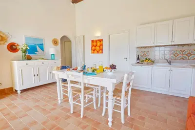 a white kitchen with a white table and chairs at Villa Rosa Dei Venti - Scopello-Villas in Scopello
