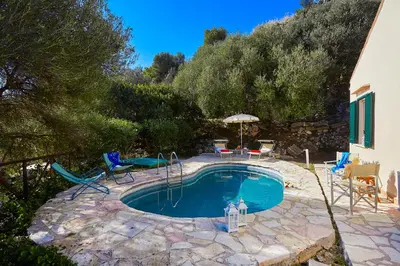 a swimming pool in a yard with chairs and an umbrella at Villa Rosa Dei Venti - Scopello-Villas in Scopello