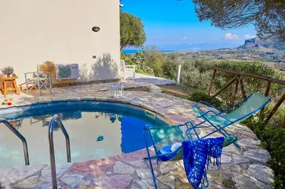 a swimming pool with two chairs and a table at Villa Rosa Dei Venti - Scopello-Villas in Scopello