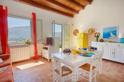 a kitchen and living room with a white table and chairs at Villa Rosa Dei Venti - Scopello-Villas in Scopello