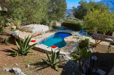 a swimming pool with an umbrella and a swimming pool at Villa Del Sol - Scopello-Villas in Scopello