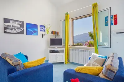 a living room with two blue chairs and a tv at Villa Del Sol - Scopello-Villas in Scopello