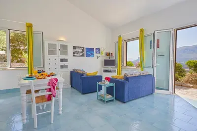 a living room with two blue chairs and a table at Villa Del Sol - Scopello-Villas in Scopello